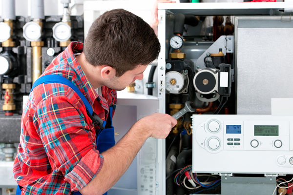 HVAC technician inspecting and repairing boiler controls in Wheat Ridge