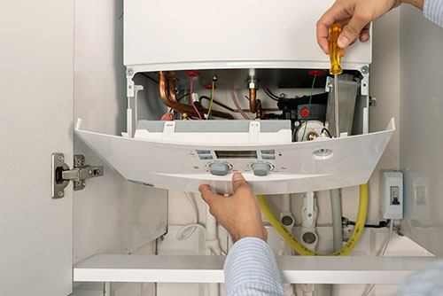 HVAC technician repairing an indoor boiler in Wheat Ridge